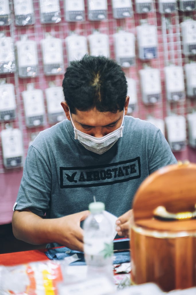 Ethnic male worker in mask selling accessories in shop